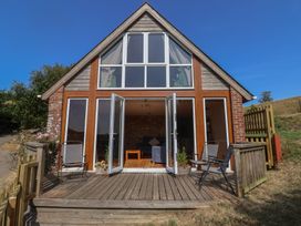 A building with double doors and chairs on a wooden deck at The Linhay Cotleigh Nr. Honiton