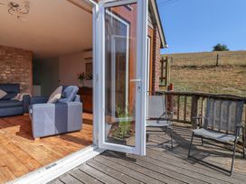 A living room with a blue sofa and chairs opening to a wooden deck at The Linhay Cotleigh Nr. Honiton