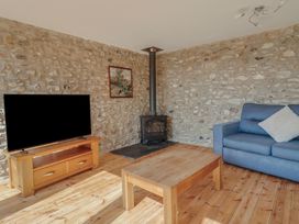 A living room with a television and a wood stove at The Linhay in Cotleigh Nr. Honiton