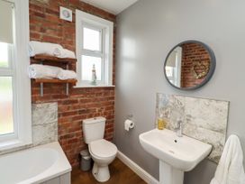 A bathroom with a bathtub, toilet, sink, and towels at Farnecrest in Seahouses