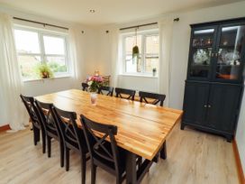 A dining room with a wooden table and black chairs at Alma House in Seahouses