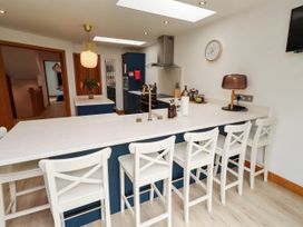 A kitchen with an island and bar stools at Alma House in Seahouses