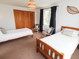 A bedroom with two beds and a wardrobe at Alma House in Seahouses