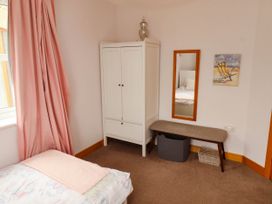 A bedroom with a bed, wardrobe, mirror, bench, and basket at Alma House in Seahouses