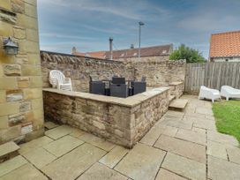 An outdoor seating area with a stone wall and furniture at Alma House in Seahouses