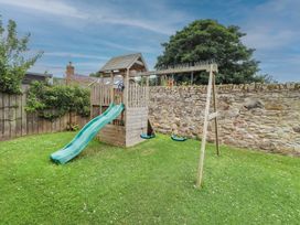 A garden with a playhouse and slide at Alma House in Seahouses
