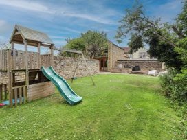A garden with a playhouse, slide, and swing at Alma House in Seahouses