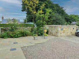 An outdoor area with a car parked and plants near a stone wall at Alma House in Seahouses