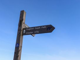 A signpost indicating the England Coast Path and Craster 3¾ miles