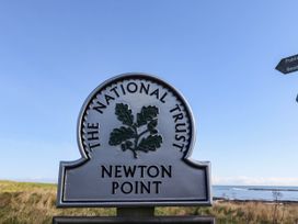 A sign for The National Trust at Newton Point with a coastline in the background