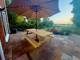 A garden with a wooden table and umbrella at Fables Cottage in Otley, Suffolk