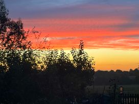 A sunset view with trees in a garden at Fables Cottage in Otley, Suffolk