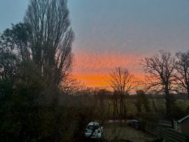 A sunset view with trees and a car at Fables Cottage in Otley, Suffolk