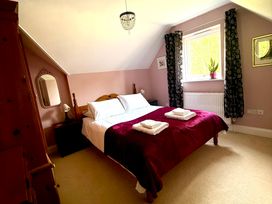 A bedroom with a bed and chair at Fables Cottage in Otley, Suffolk