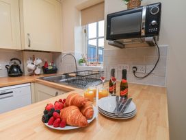 A kitchen with a sink, microwave, and food items at The Cosy Haven in Malton