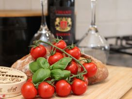 A kitchen counter with tomatoes, basil, bread, wine bottle, and wine glasses at The Cosy Haven in Malton