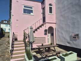 An outdoor area with a pink building, table, and planters at 2 Mill Green Court in Lyme Regis