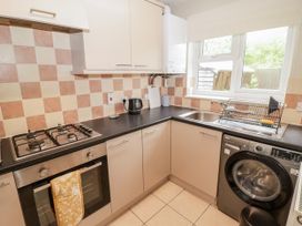 A kitchen with stove, oven, kettle, sink, and washing machine at 7 Cwrt Y Cadno in Llantwit Major