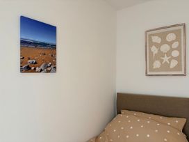 A bedroom with a beach photo and shell artwork at 7 Cwrt Y Cadno in Llantwit Major