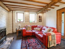 A living room with a red sofa and fireplace at Pandy Farmhouse