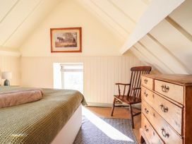 A bedroom with a bed, chair, and dresser at Pandy Farmhouse