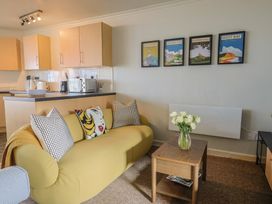 A living room with a yellow sofa and a vase of flowers at 4 Kingfisher Court West Bay