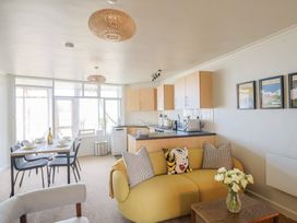 A living room with a sofa and dining area at 4 Kingfisher Court in West Bay