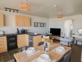 A kitchen and living room with appliances and dining setup at 4 Kingfisher Court West Bay