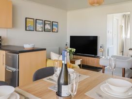 A living room with a dining table and a television at 4 Kingfisher Court, West Bay