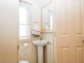 A bathroom with a sink, mirror, and towel rack at The Hideaway in Portesham