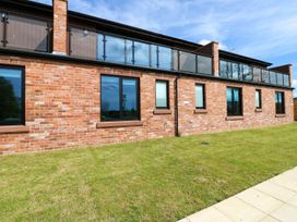 An exterior view of a house with brick wall and balcony at Sycamore Cottage in Frizington