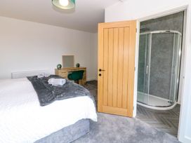 A bedroom with a bed, dresser, towels, and attached shower at Sycamore Cottage in Frizington