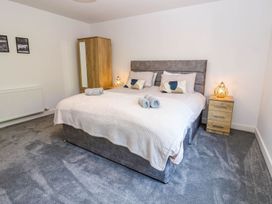 A bedroom with a bed, bedside table, wardrobe, and towels at Sycamore Cottage in Frizington