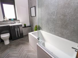 A bathroom with a bath tub, toilet, and sink at Sycamore Cottage in Frizington