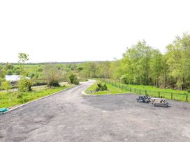 A pathway with trees and a lake at Sycamore Cottage Frizington