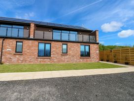 A house with a balcony and grass area at Silver Birch Cottage in Frizington