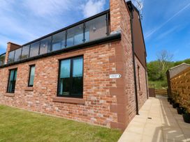 An exterior view of a brick house with a balcony at Silver Birch Cottage in Frizington