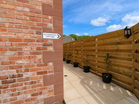 An outdoor pathway with potted plants and a sign at Silver Birch Cottage in Frizington