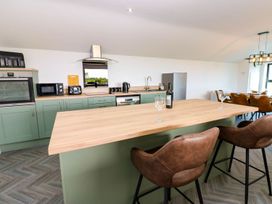A kitchen with bar stools and appliances at Silver Birch Cottage in Frizington