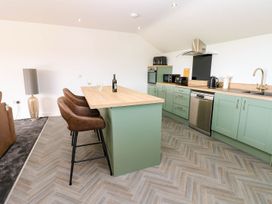A kitchen with bar stools and appliances at Silver Birch Cottage in Frizington