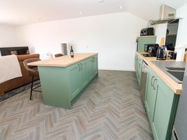 A kitchen with a green island and appliances at Silver Birch Cottage in Frizington