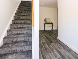 A hallway with stairs and a table with a mirror at Silver Birch Cottage in Frizington