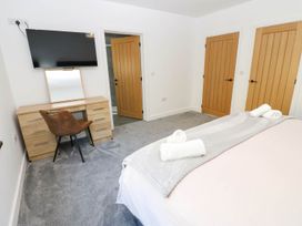 A bedroom with a bed and dresser at Silver Birch Cottage in Frizington