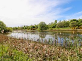 A body of water surrounded by trees and vegetation at Silver Birch Cottage in Frizington