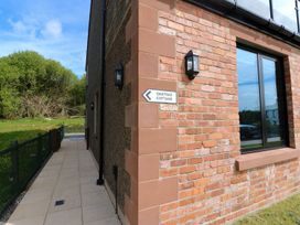 An outdoor view of Oak Tree Cottage with a pathway and sign indicating the property at Oak Tree Cottage in Frizington