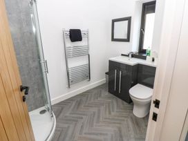 A bathroom with shower, sink, toilet and towel rail at Oak Tree Cottage in Frizington