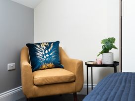 A chair with a cushion and a side table in a bedroom at 38 Ashville Avenue, Scarborough