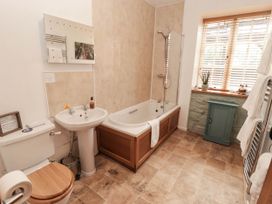 A bathroom with a bath, toilet, wash basin, and window at Ty Mawr Country House in Carmarthen