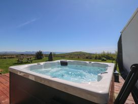 A hot tub on a wooden deck with views at Cefnbron in Caernarfon