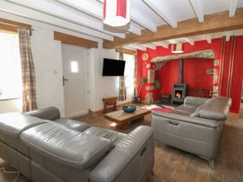 A living room with a sofa, coffee table, and television at Cefnbron in Caernarfon